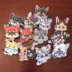 Op de afbeelding: Een verzameling van 13 kleurrijke cartoon kattenpins met verschillende uitdrukkingen. De pins zijn gemaakt van glanzend materiaal en hebben verschillende vachtkleuren, ogen en neuzen.