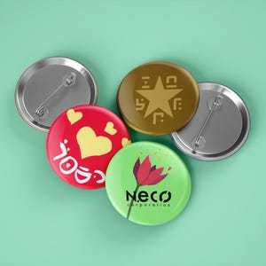 Può includere: Quattro diverse spille da balia. Una è rossa con un cuore giallo e testo bianco. Un'altra è verde con un fiore rosso e il testo "Neco Corporation". Una terza è marrone con una stella dorata e forme geometriche. L'ultima è argentata con un retro a spilla.