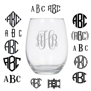 Op de afbeelding: Een verzameling van verschillende monogramontwerpen voor een wijnglas. De ontwerpen omvatten een diamant, een cirkel, een schild, een hart, een krans, een schrijfletter en een eenvoudig bloklettertype. De ontwerpen zijn allemaal in zwart en wit.