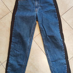 Peut inclure: Un jean bleu denim avec des panneaux latéraux rayés brun et vert.
