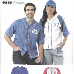 May include: Simplicity sewing pattern S3241 featuring baseball-style shirts. The pattern includes two shirt designs, one blue with the number 83 and another white with blue sleeves and the number 27. The pattern is easy-to-sew and designed and printed in the USA.