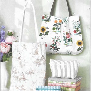 May include: Simplicity pattern S3293 for bags and pouches. Includes a tall tote with white rope handles and brown toile print, a wide tote with floral botanical illustrations, a striped zippered pouch, and a blue patterned zippered pouch.