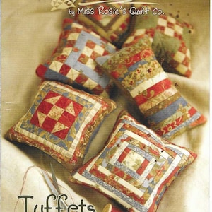 May include: A pattern booklet titled Schnibbles by Miss Rosie's Quilt Co. featuring Tuffets RQC #432. The cover displays five small, square, quilted fabric pillows with various patchwork designs in red, blue, cream, and green, alongside scissors and thread.