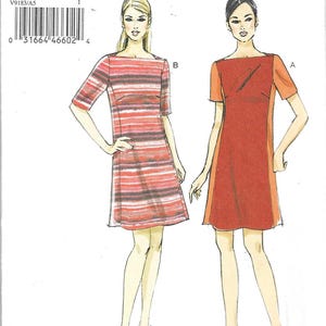 May include: A Very Easy Vogue sewing pattern, V9183, featuring two dress designs. One dress is red with orange sleeves, and the other is a red and white striped pattern. The pattern includes sizes 6-8-10-12-14 and is custom fit for A, B, C, and D cup sizes.