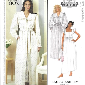 May include: McCall's sewing pattern featuring vintage 80s designs. The pattern includes options for sizes XS-L. The image shows a woman wearing a long, white floral print robe with a ruffled collar and tie.