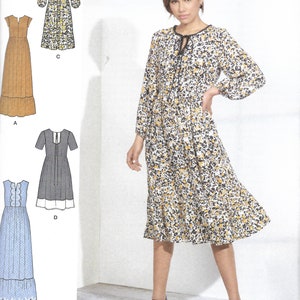 May include: Simplicity sewing pattern S8872 featuring four dress designs. The main image shows a woman wearing a floral print dress with long sleeves. The pattern includes sizes 12-20. The Simplicity logo and "Since 1927" are visible.