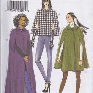 May include: A sewing pattern envelope labeled V8959 Very Easy Vogue for sizes Xsm-Sml-Med. The illustration displays three cape designs: a long purple cape, a black and white houndstooth patterned cape, and a shorter olive green cape with a collar.