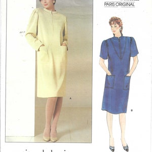 May include: Vogue Patterns Paris Original sewing pattern featuring two dress designs. One dress is long-sleeved and pale yellow, the other is short-sleeved and blue. Both dresses have a zip-up neckline and pockets. The pattern is labeled "pierre balmain".