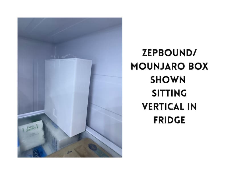 May include: A white rectangular box labeled ZEPBOUND/MOUNJARO is shown vertically inside a refrigerator. The box is the primary focus, with the fridge interior visible in the background. The box is sitting on top of other items.