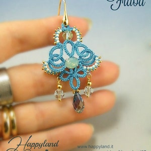 Peut inclure: Une paire de boucles d'oreilles pendantes bleues et dorées avec une pierre précieuse bleu clair et des accents de cristal. Les boucles d'oreilles sont étiquetées "Fiaba" et "Happyland".