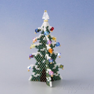 May include: A small, white and green beaded Christmas tree with a white star on top and colourful beads for ornaments. The tree is standing on a light blue surface.