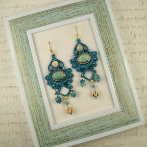 Peut inclure: Une paire de boucles d'oreilles en crochet bleu turquoise avec des perles vertes et dor&eacute;es et une pierre vert clair au centre de chaque boucle d'oreille.