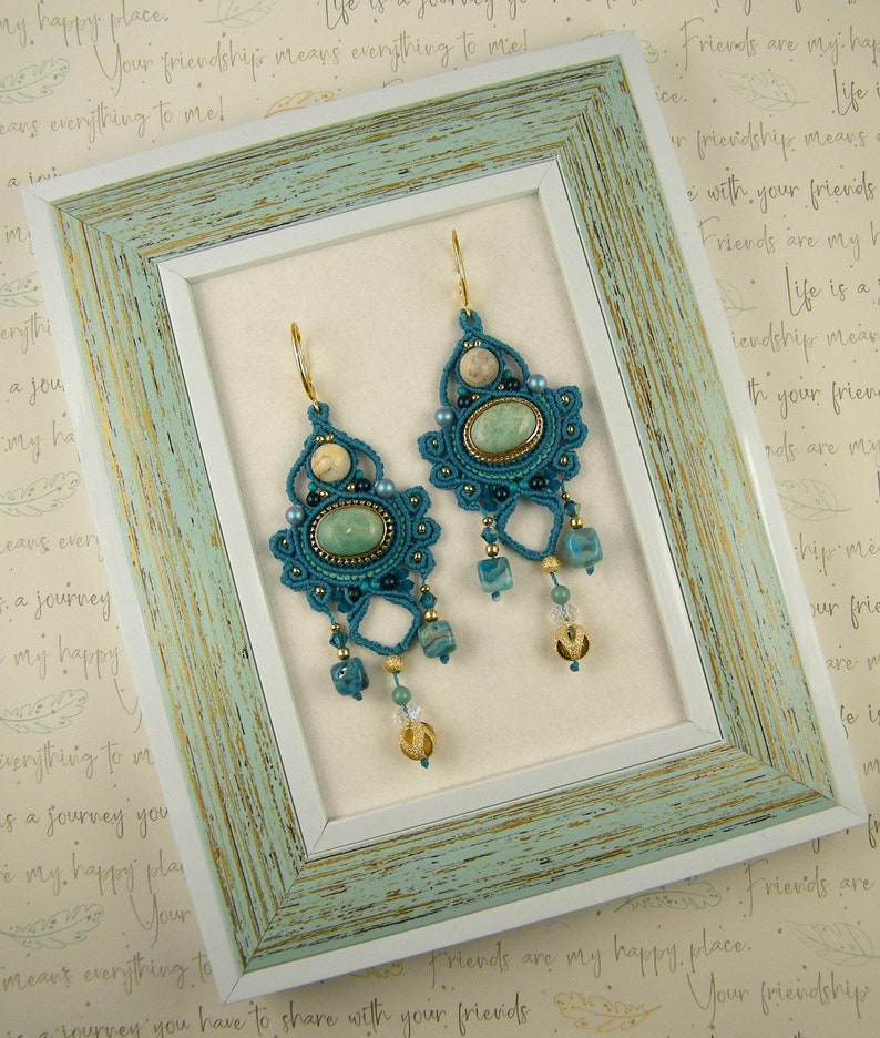 Peut inclure: Une paire de boucles d'oreilles en crochet bleu turquoise avec des perles vertes et dor&eacute;es et une pierre vert clair au centre de chaque boucle d'oreille.