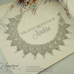 May include: A silver and gold beaded necklace with a delicate lace design. The necklace is labeled "BRAND ROMANCE Nadira".