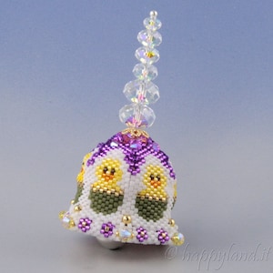May include: A white, purple, and green beaded bell with a crystal top. The bell is decorated with yellow chicks and purple flowers.