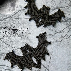 May include: Two black macrame bat wall hangings with black beads. The bats are made using a knotting technique and have a detailed design.