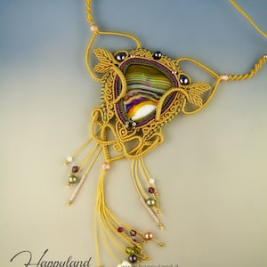 Peut inclure: Un collier noué or et violet avec un grand pendentif en agate vert, blanc et violet. Le collier a un pompon avec plusieurs brins de cordon doré et de perles.