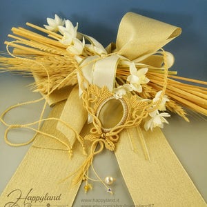 May include: A gold macrame necklace with a large, oval-shaped agate pendant. The necklace is displayed on a golden ribbon and wheat stalks.