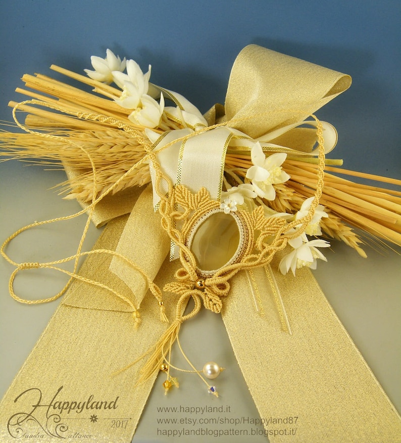 May include: A gold macrame necklace with a large, oval-shaped agate pendant. The necklace is displayed on a golden ribbon and wheat stalks.