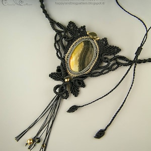 May include: A black macrame necklace with a gold and brown agate stone pendant. The necklace has a tassel and is made with a delicate knotting technique.