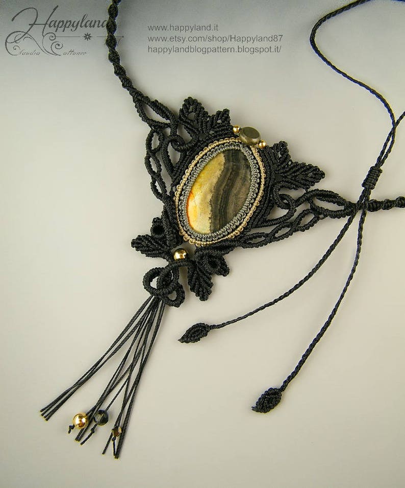 May include: A black macrame necklace with a gold and brown agate stone pendant. The necklace has a tassel and is made with a delicate knotting technique.