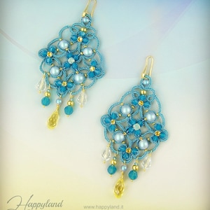 May include: A pair of turquoise blue and gold dangle earrings with pearl and crystal accents. The earrings feature a delicate, intricate design with a floral motif.