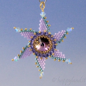 Puede incluir: Un adorno de estrella de cuentas moradas y verdes con un centro de cristal. La estrella cuelga de un lazo dorado.