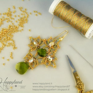 May include: A gold and green beaded earring with a teardrop-shaped green crystal pendant. The earring is on a white surface with a spool of gold thread, a needle, and a pair of scissors.