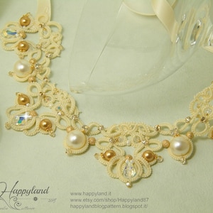 May include: A delicate white crocheted necklace with gold and clear beads. The necklace is displayed on a light green surface.