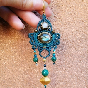 Peut inclure: Boucle d'oreille en macram&eacute; bleu sarcelle et or avec une pierre de labradorite, une pierre blanche et des perles vertes.