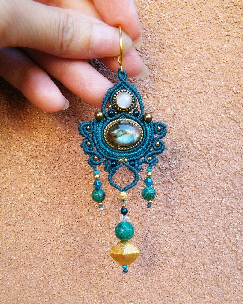 Peut inclure: Boucle d'oreille en macram&eacute; bleu sarcelle et or avec une pierre de labradorite, une pierre blanche et des perles vertes.