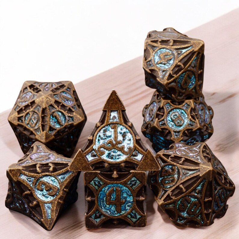 May include: Set of seven metal dice with a bronze and blue iridescent finish. The dice are detailed with intricate designs and feature numbers 1 through 6.