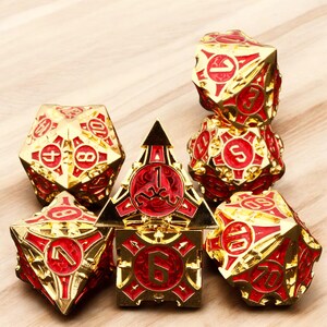 May include: Set of seven gold and red metal dice with intricate designs. The dice are numbered 1 through 6 and have a unique, ornate style.