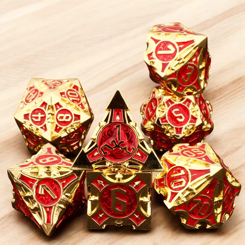 May include: Set of seven gold and red metal dice with intricate designs. The dice are numbered 1 through 6 and have a unique, ornate style.