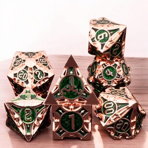 May include: A set of seven metal dice with a rose gold finish and green accents. The dice are numbered 1 through 20 and feature intricate designs.