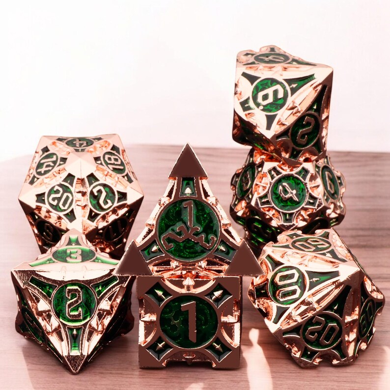 May include: A set of seven metal dice with a rose gold finish and green accents. The dice are numbered 1 through 20 and feature intricate designs.
