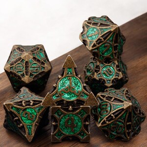 May include: A set of seven metal dice with a green and gold finish. The dice are detailed with intricate designs and have numbers from 1 to 10.