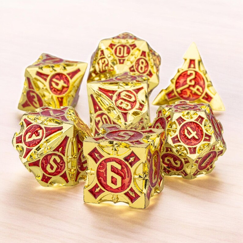 May include: Set of seven gold and red metal dice with a detailed design. The dice are numbered 4, 6, 8, 10, 12, and 20.