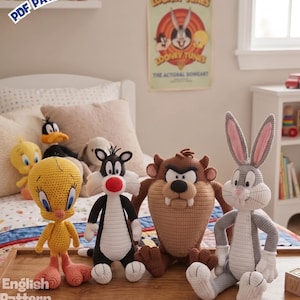 Może przedstawiać: Cztery szydełkowe lalki przedstawiające postacie z Looney Tunes, w tym żółtego Tweety'ego, czarno-białego kota Sylwestra, brązowego Diabła Tasmańskiego i szarego Królika Bugsa. Lalki stoją na drewnianej powierzchni z widocznym napisem PDF PATTERN.