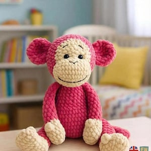 Puede incluir: Un mono rosa de ganchillo hecho a mano con cara, manos y pies color crema. El mono tiene orejas grandes y rosas y está sentado sobre una superficie de madera. El texto "PDF PATTERN" está en la esquina superior izquierda. Este juguete blando es perfecto para un cuarto de bebé.