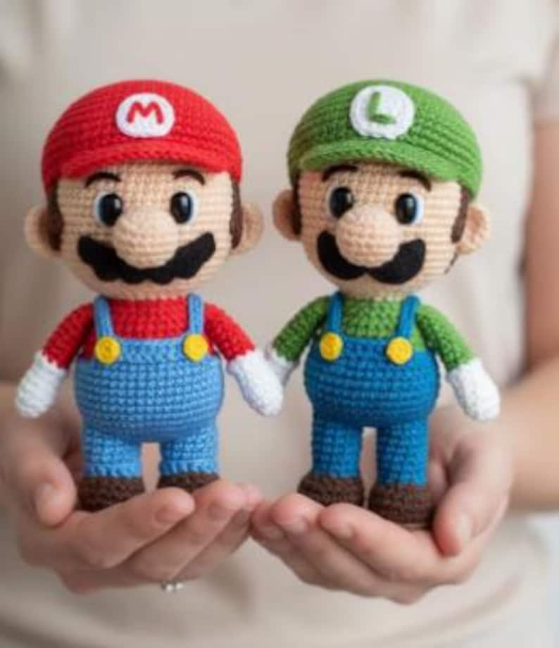 May include: Two handmade crochet dolls of Mario and Luigi. Mario wears a red hat with a white "M", a red shirt, blue overalls, and brown shoes. Luigi wears a green hat with a white "L", a green shirt, blue overalls, and brown shoes.