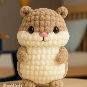 Puede incluir: Un juguete de hámster hecho a mano con ganchillo en tonos marrón y crema, con ojos negros y una nariz rosa. El peluche está de pie sobre una superficie de madera. El texto de la imagen dice "PDF PATTERN" y "English Pattern".