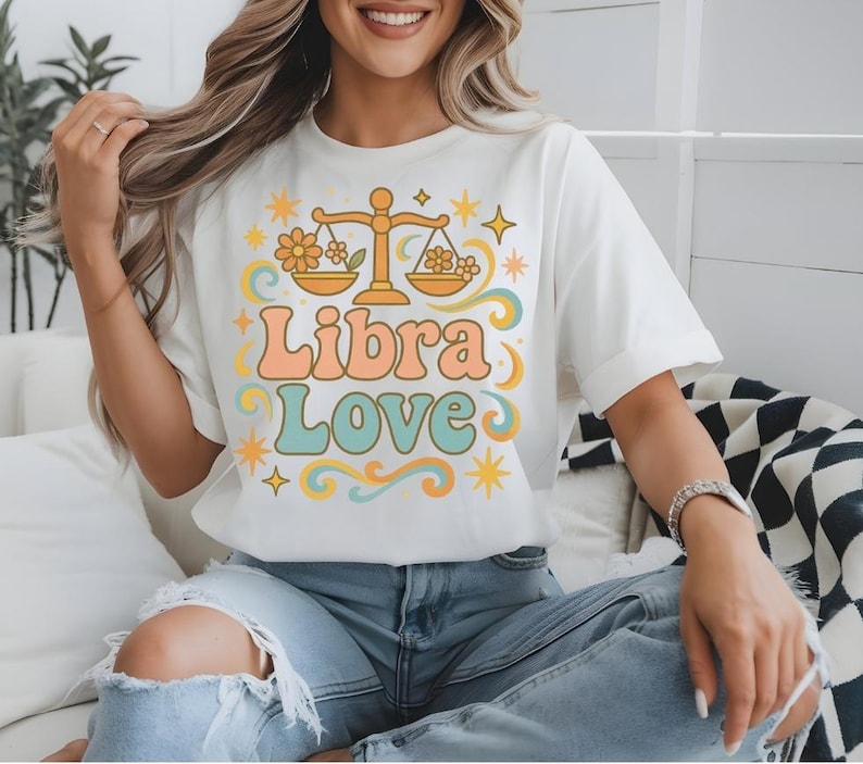以下が含まれることがあります： レトロなスタイルで、天秤座の星座のシンボルと「Libra Love」のテキストが描かれた白いTシャツです。