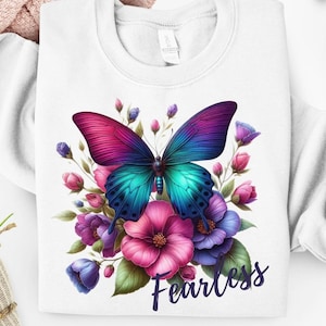 May include: White sweatshirt with a colourful butterfly design, featuring pink, teal, and purple wings, and surrounded by flowers. The word "Fearless" is written in a script font. A casual, comfortable top.