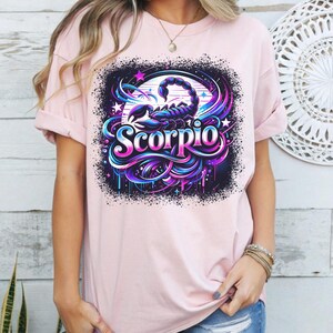 May include: Pink t-shirt featuring a graphic design of a scorpion with the word "Scorpio" in a colourful, stylised font.