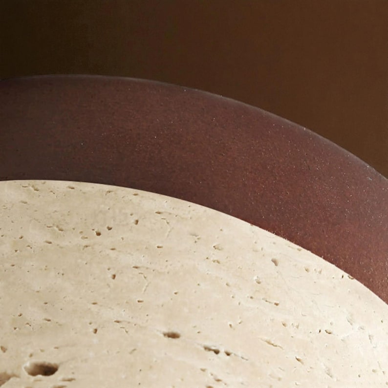 May include: Close-up of two curved surfaces. The bottom surface is a light beige with a textured, porous appearance. The top surface is a smooth, dark brown, creating a contrast in color and texture. The background is a gradient of brown.