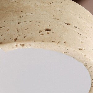 May include: Close-up of a light beige, textured, rounded object with small holes and a smooth, white, curved surface. The object has a natural, porous appearance.