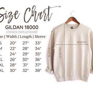 Size chart for a Gildan 18000 unisex sweatshirt. The chart shows the width, length, and sleeve length for sizes S, M, L, XL, 2XL, and 3XL. The chart is displayed next to a beige sweatshirt hanging on a hanger. Labeled SLEEVE,LENGTH, and WIDTH