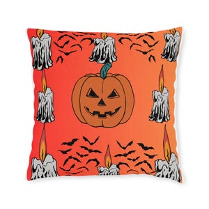 Puede incluir: Cojín cuadrado con temática de Halloween con un fondo degradado naranja. El diseño presenta una calabaza sonriente, velas encendidas y siluetas de murciélagos. Un artículo decorativo festivo.
