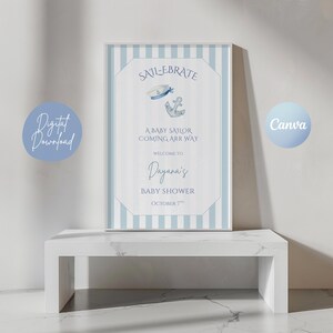Pode incluir: Uma placa de chá de bebê emoldurada com tema náutico. A placa apresenta um fundo listrado azul e branco com as palavras "SAIL-EBRATE" e "A BABY SAILOR COMING ARR WAY". Também inclui o nome "Dayana's" e a data "OCTOBER 7th".